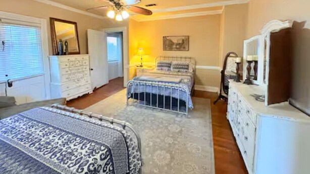 A bedroom with a bed, a dresser, a nightstand, a lamp, and a ceiling fan.
