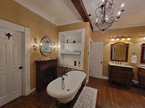 A bathroom with a freestanding bathtub, a vanity with a mirror, and a chandelier. - The Steamboat House, Captain's Quarters-Bed & Breakfast Style Experience (Natchitoches)