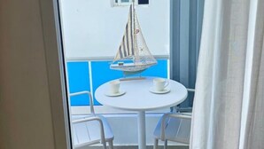 A balcony with a white table, two chairs, a small sailboat decoration, and a window. - ANYA 5 Chic Coastal Oasis • King Bed & Balcony (Bayahíbe)