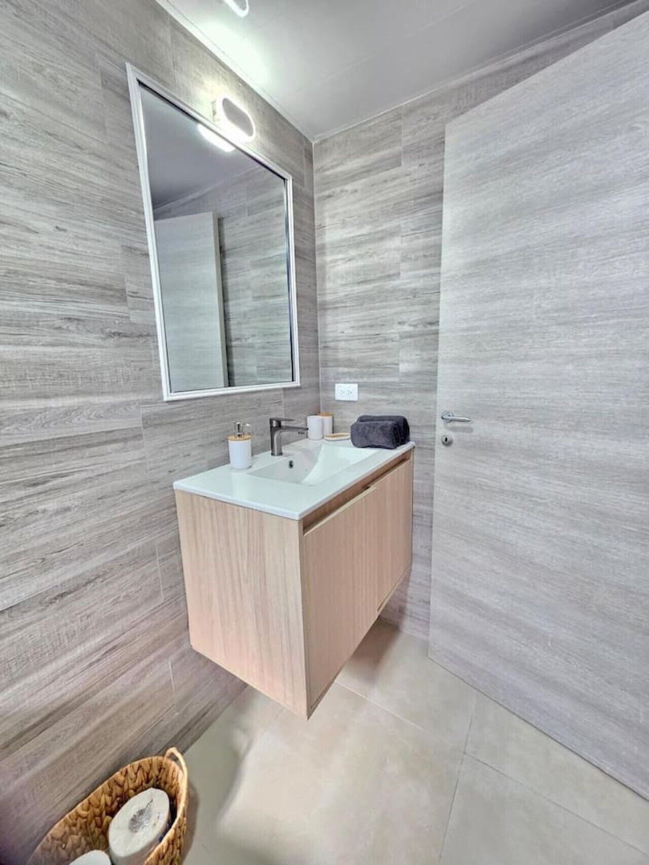 Un baño moderno con un espejo grande, un lavabo y un armario.