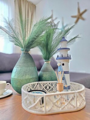 A table with decorative items including vases, a lighthouse model, and a macrame tray. - ANYA 5  Caribbean Apartment 1BR APT Pool view (Bayahíbe)