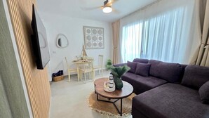 A living room with a sofa, a round coffee table, a ceiling fan, and a dining area with chairs and a table. - ANYA 5 Chic Coastal Oasis • King Bed & Balcony (Bayahíbe)