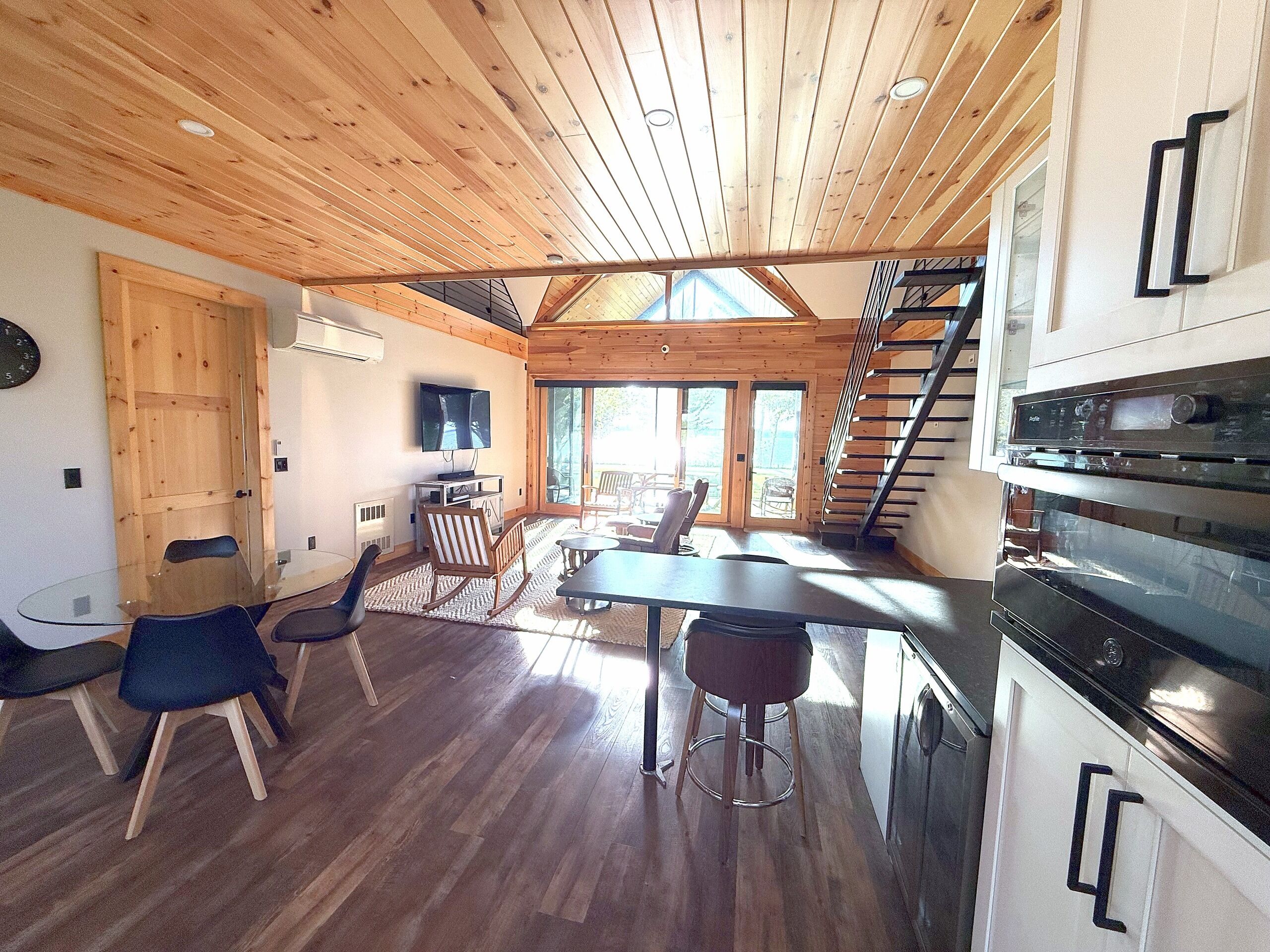 Un intérieur en bois comprenant un coin repas, une cuisine et un escalier menant à un niveau supérieur.