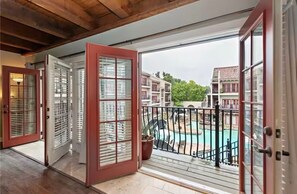Ein Balkon mit Pool und Blick auf umliegende Gebäude.