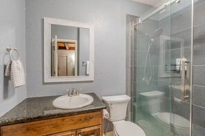 Une salle de bain avec un lavabo blanc, des toilettes et une douche à parois de verre.