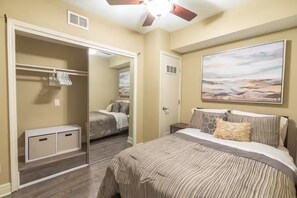 Une chambre à coucher avec un lit, une armoire, un ventilateur de plafond et un tableau accroché au mur.