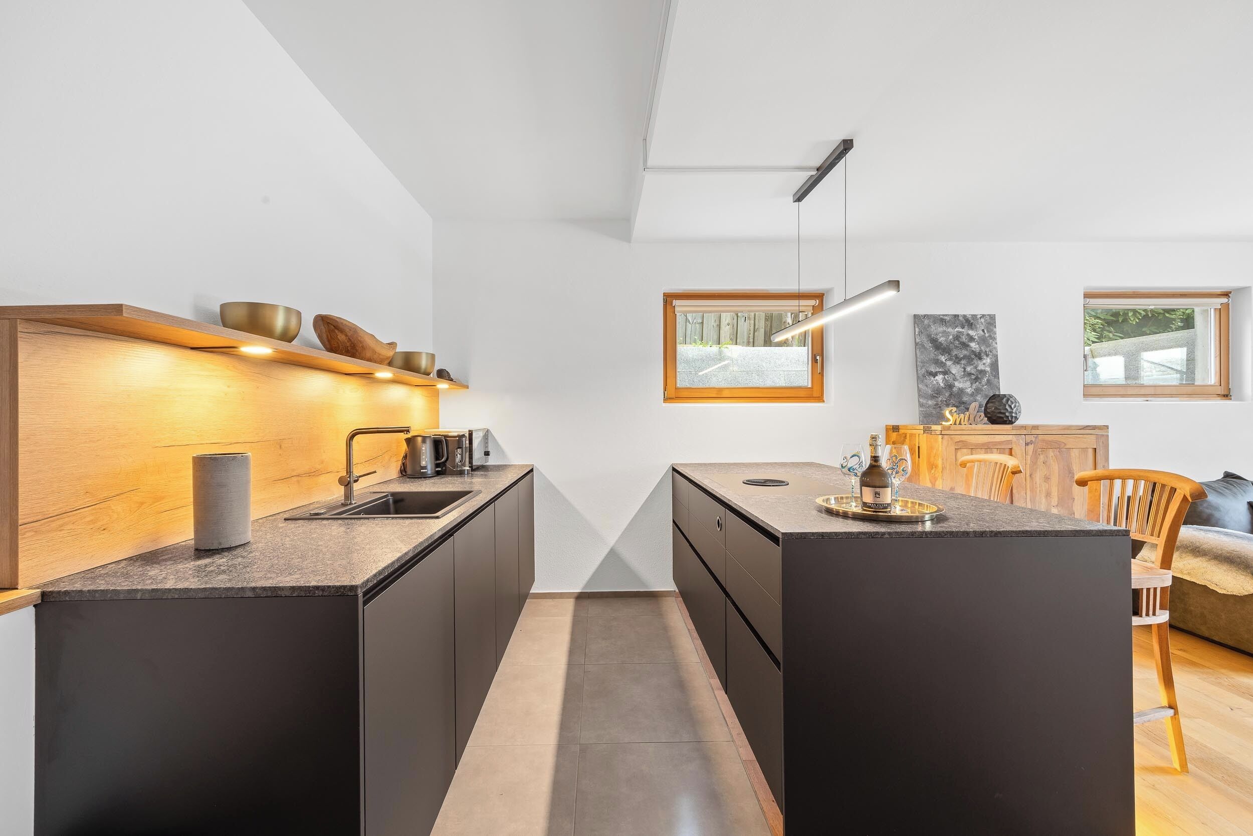 A modern kitchen with a central island, built-in appliances, and a dining area with a wooden table and chairs.