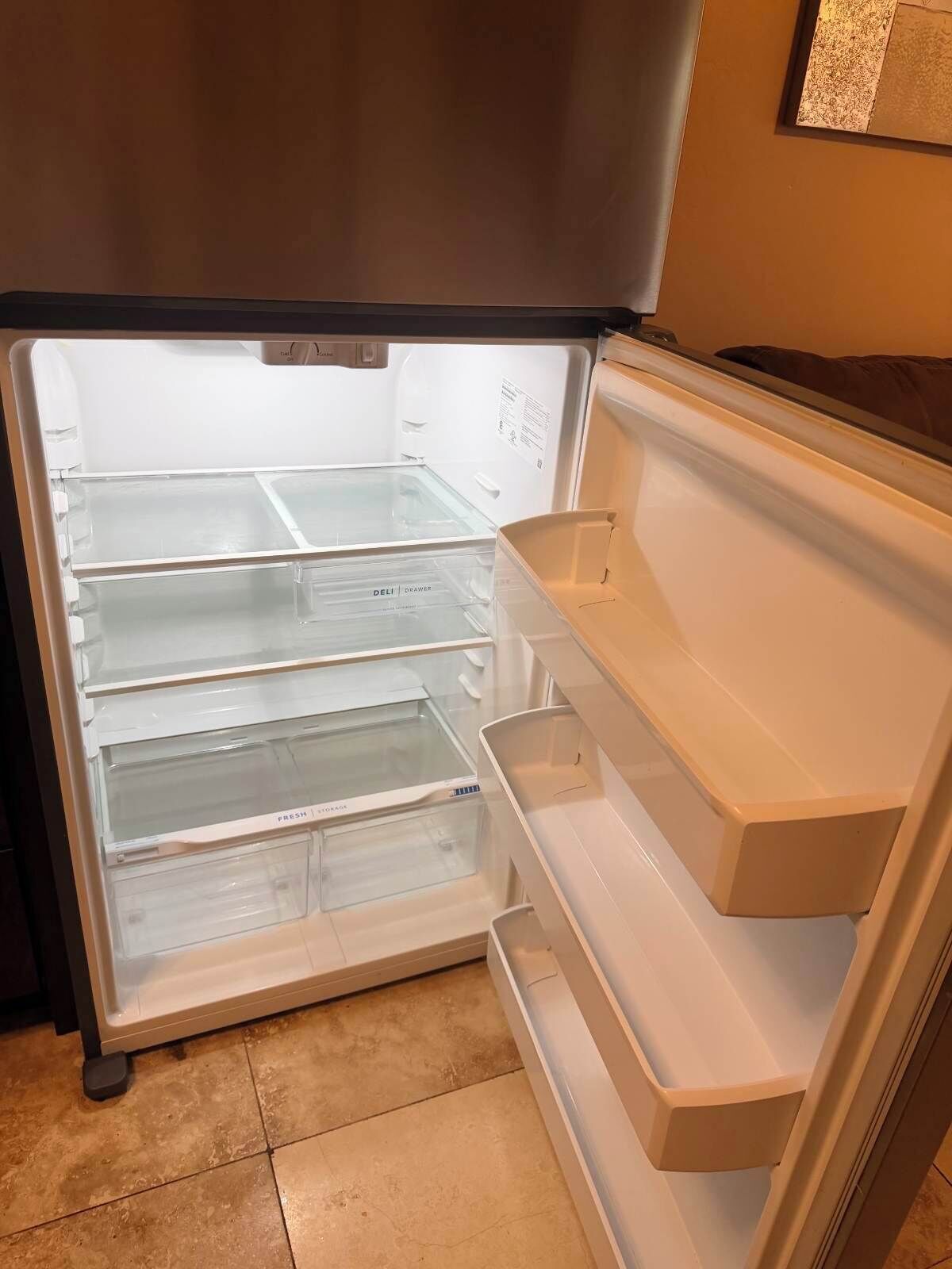 An interior of a refrigerator with multiple transparent shelves and a freezer compartment.
