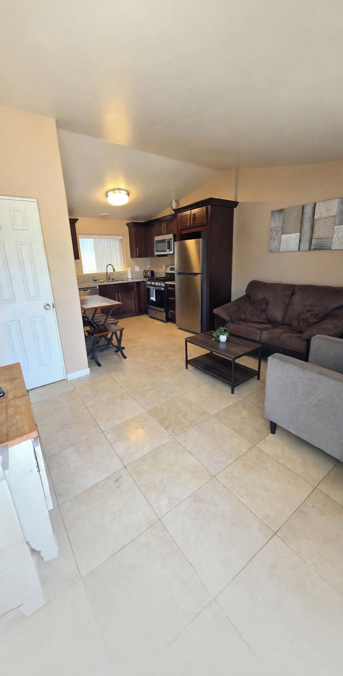 A living room with a sofa, a coffee table, and a kitchen in the background.
