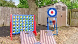 A backyard with a wooden shed, a target board, and two American flag-themed mats. - Ohio State, Short North, Off Street Parking, Games, Firepit (Columbus)
