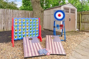 A backyard with a wooden shed, a target board, and two American flag-themed mats. - Ohio State, Short North, Off Street Parking, Games, Firepit (Columbus)