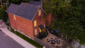 A two-story brick house with a fenced backyard, a stop sign, and a street view. - Ohio State, Short North, Off Street Parking, Games, Firepit (Columbus)