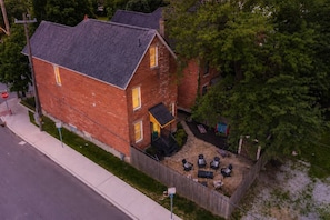 A two-story brick house with a fenced backyard, a stop sign, and a street view. - Ohio State, Short North, Off Street Parking, Games, Firepit (Columbus)