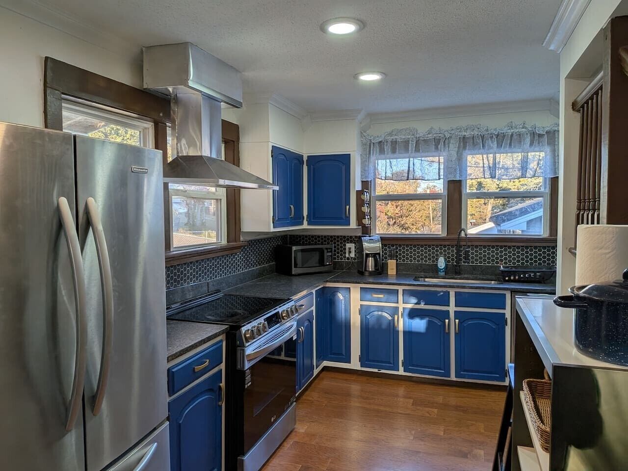 A kitchen with blue cabinets, stainless steel appliances, a microwave, and a stove.