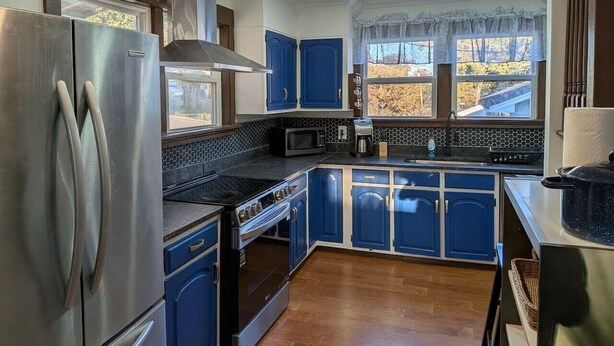 A kitchen with blue cabinets, stainless steel appliances, a microwave, and a stove. - Gingerbread Home | Quiet Stay | 30+ Day Ready (Chattanooga)