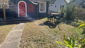 A residential property with a red door, a visible house number, a paved driveway, and a small outdoor seating area. - Gingerbread Home | Quiet Stay | 30+ Day Ready (Chattanooga)