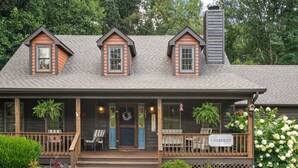 A wooden house with a porch, multiple windows, and a sign reading 'CREEKSIDE'. -  NEW LISTING 3BR CABIN NEAR FALLS CREEK FALLS, LARGE SCREENED IN PATIO HOT TUB, (Spencer)