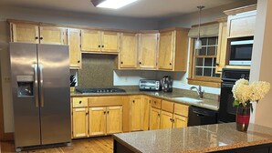 A kitchen with wooden cabinets, a stainless steel refrigerator, a built-in oven, and a granite countertop. -  NEW LISTING 3BR CABIN NEAR FALLS CREEK FALLS, LARGE SCREENED IN PATIO HOT TUB, (Spencer)