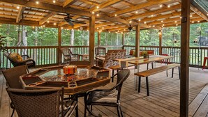 An outdoor deck with wooden furniture, a glass-top table, and string lights. -  NEW LISTING 3BR CABIN NEAR FALLS CREEK FALLS, LARGE SCREENED IN PATIO HOT TUB, (Spencer)