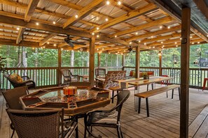 Eine Terrasse im Freien mit Holzmöbeln, einem Tisch mit Glasplatte und Lichterketten.