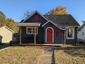 A two-story house with a red door, a covered porch, and a small front yard. - Gingerbread Studio w/ Private Entry | 31+ Days (Chattanooga)