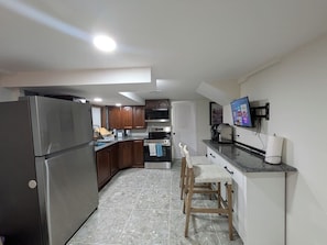 A kitchen with a refrigerator, oven, and a dining area with chairs. - Gingerbread Studio w/ Private Entry | 31+ Days (Chattanooga)