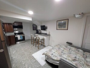 A compact kitchen with a microwave, stove, and bar stools. - Gingerbread Studio w/ Private Entry | 31+ Days (Chattanooga)