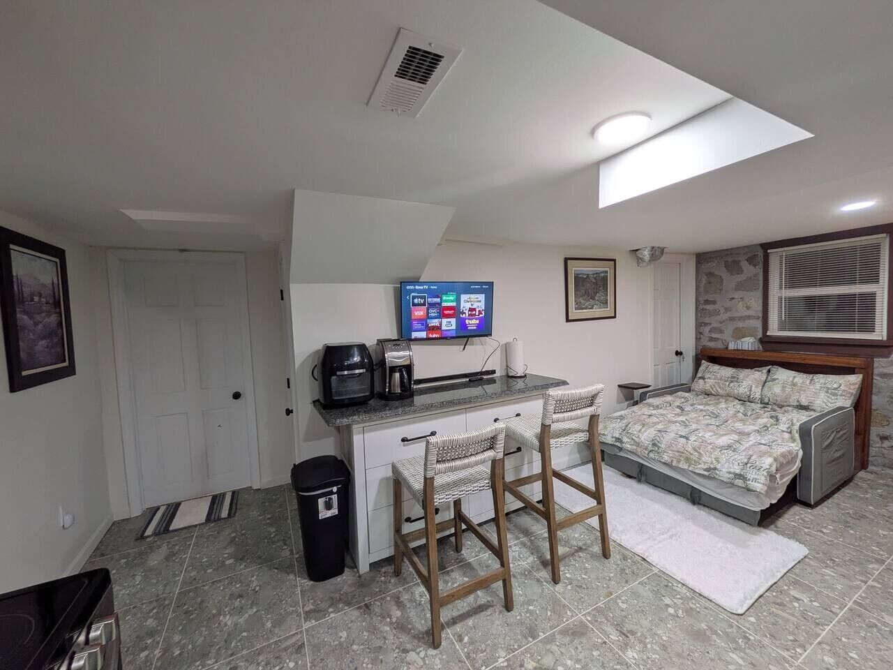 A compact room with a kitchenette, a bed, and a TV.