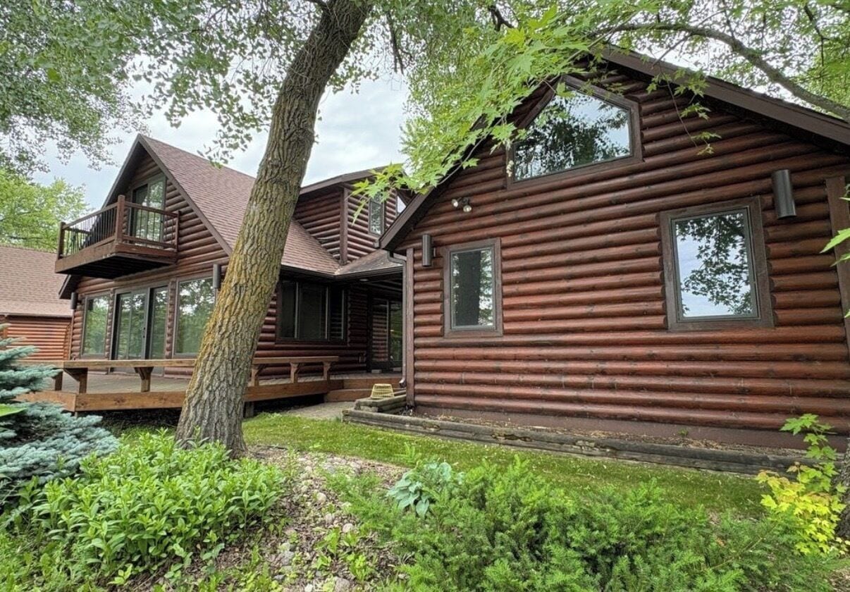 Eine Blockhütte mit Balkon, großen Fenstern und einer Veranda.