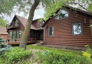A log cabin with a balcony, large windows, and a porch area.