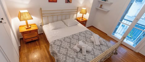 A bedroom with a bed, two bedside tables with lamps, a wardrobe, and a window with a view.