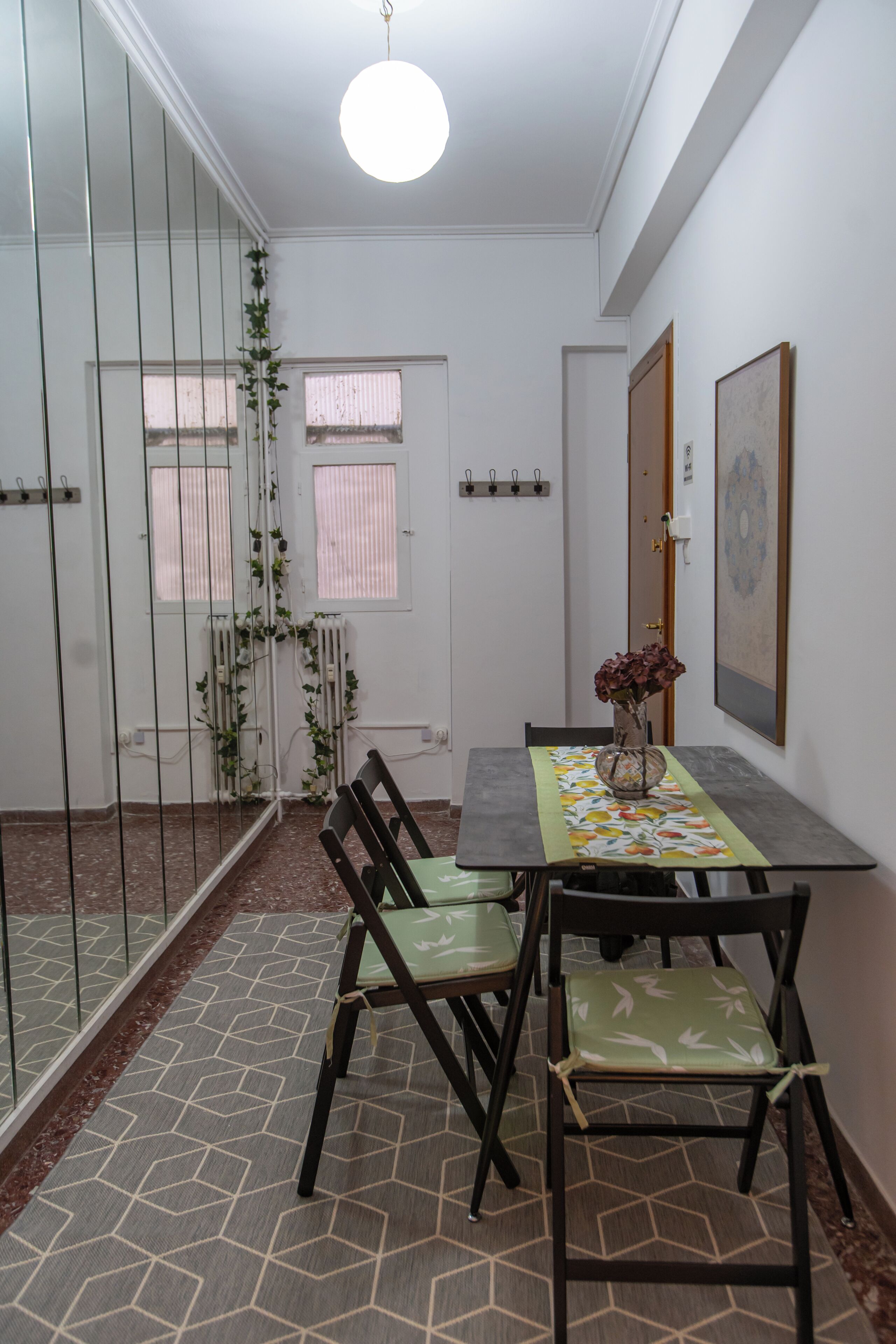 A dining area with a table and chairs, a radiator, a window with blinds, and a door with a lock.
