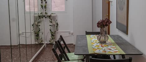 A dining area with a table and chairs, a radiator, a window with blinds, and a door with a lock.