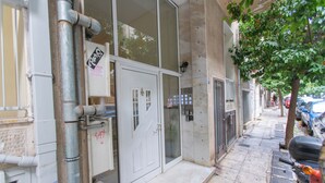 A building facade with a door, windows, and a small tree on the sidewalk. -  Live Like a Local, Steps From Acropolis | Homey, Roomy & Sleeps 4 (Athina)