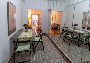 A dining area with a long table, chairs, and a patterned floor. -  Live Like a Local, Steps From Acropolis | Homey, Roomy & Sleeps 4 (Athina)