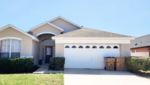 A two-story house with a garage, a front door, and a small porch area. - Lovely home, Quiet Escape Near Disney (Kissimmee)