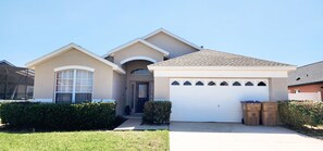 A two-story house with a garage, a front door, and a small porch area. - Lovely home, Quiet Escape Near Disney (Kissimmee)