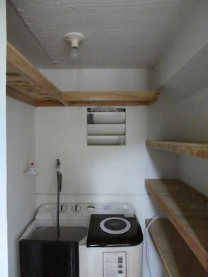 A compact laundry room with a washing machine, a dryer, and a small window.