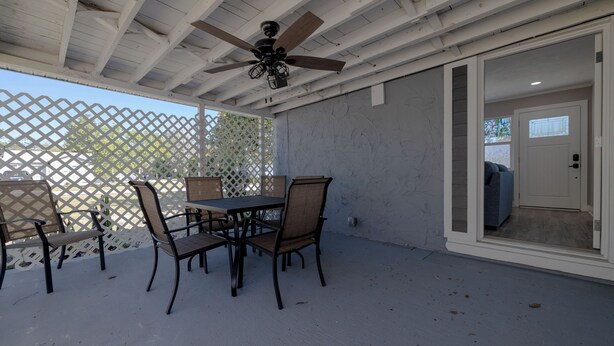 A covered patio with a ceiling fan, outdoor furniture, and a sliding glass door leading to an interior space.