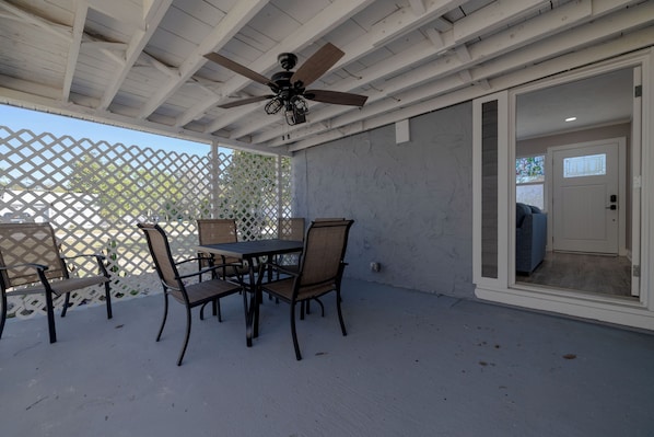 A covered patio with a ceiling fan, outdoor furniture, and a sliding glass door leading to an interior space.