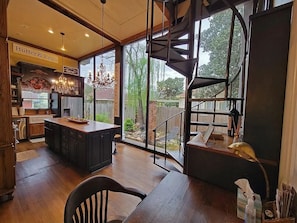 A modern kitchen with a central island, a chandelier, and a view of the backyard through large windows.