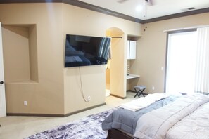 A bedroom with a bed, a television mounted on the wall, a desk, and a chair. - Spacious 4-Bedroom House /Self Check-In/Wifi/King Bed/EV Charger/Newly Renovated (Modesto)
