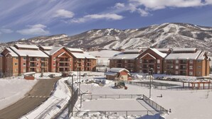 Un resort cubierto de nieve con varios edificios de techos rojos, cielo despejado y montañas al fondo.