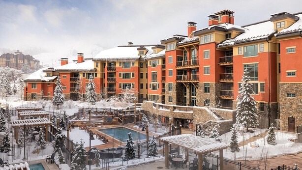 Hotel de varios pisos con un patio central que cuenta con una piscina, rodeado de árboles cubiertos de nieve y zonas de estar al aire libre.