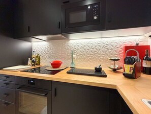 A modern kitchen with a microwave, a kettle, and a coffee maker on the counter. - Beautiful apartment in a prime location in Crans-Montana (Crans-Montana)