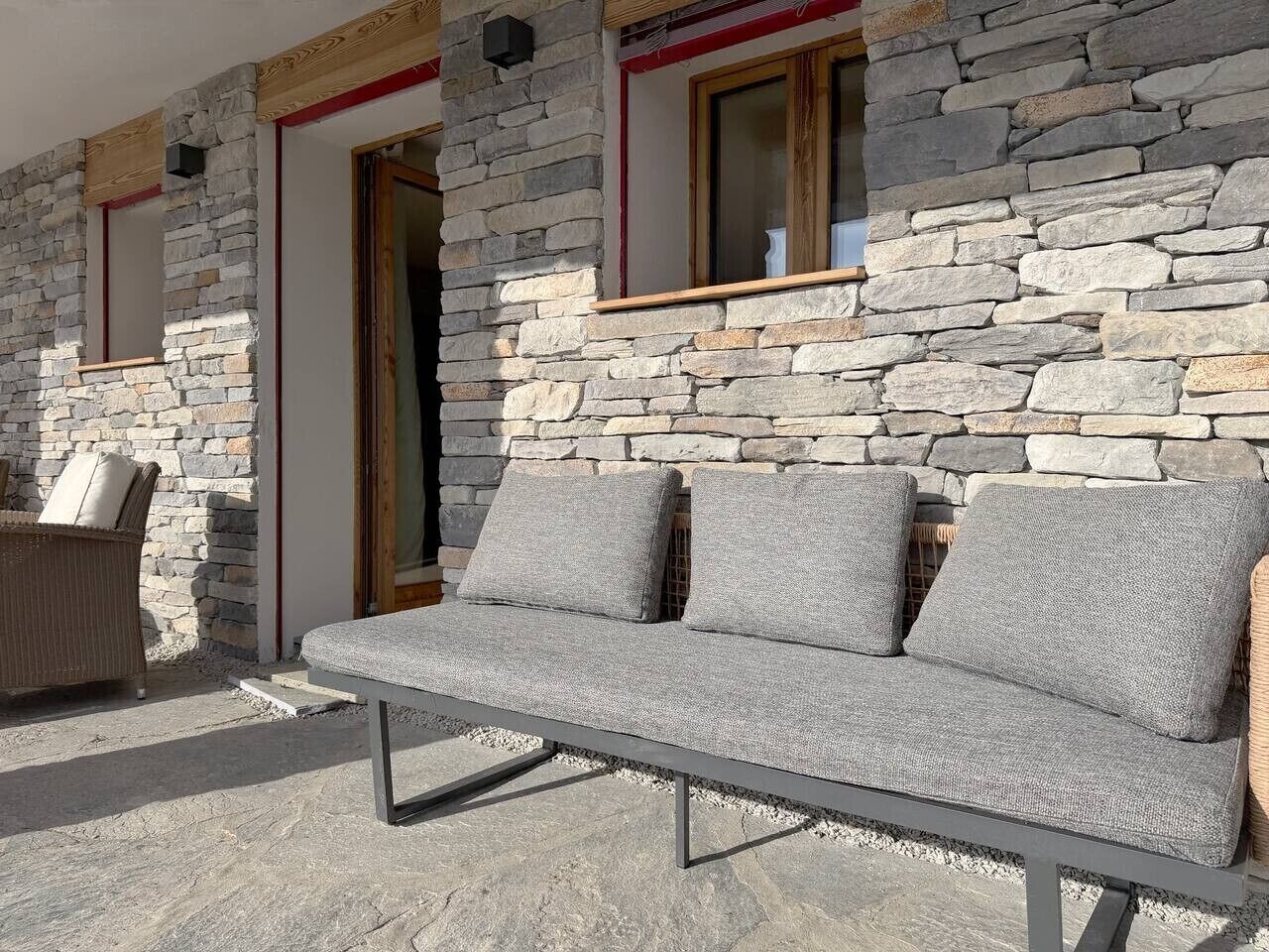 A stone wall exterior with a built-in bench and a door.