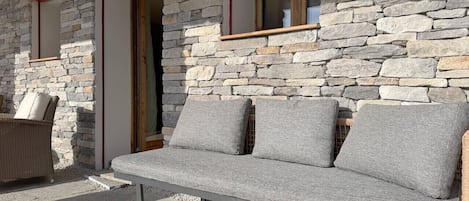 A stone wall exterior with a built-in bench and a door.