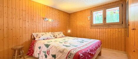 A room with wooden walls and a bed with a floral bedspread.