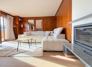 Ein modernes Wohnzimmer mit einem Ecksofa, einem Couchtisch, einem Kamin und einem Fernseher.