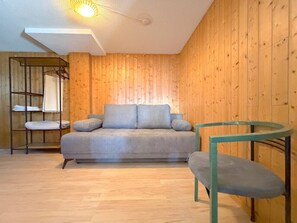A room with a sofa, a chair, and a wooden wall. - A fully equipped chalet with a magnificent view of the Alps! (Crans-Montana)